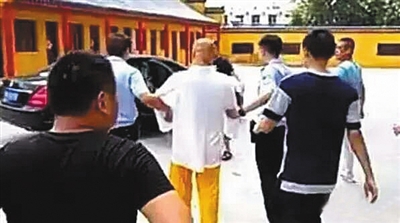 Thích Quảng Văn bị cảnh sát áp giải lên xe. Ảnh: Beijing News
