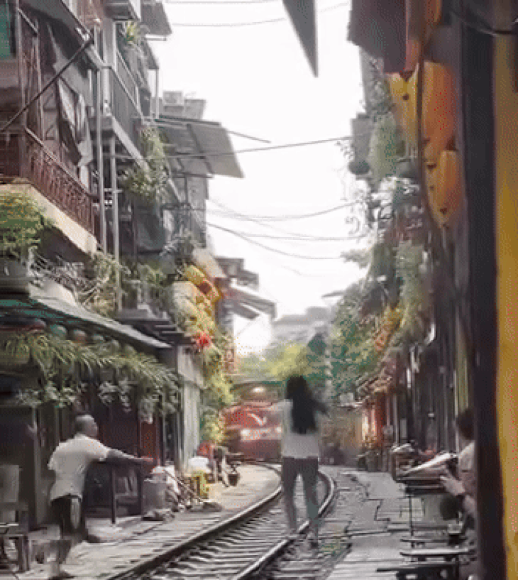 Vụ cô gái lao ra đường ray chụp ảnh: Lập biên bản xử lý chủ quán cà phê đường tàu- Ảnh 1. Người đàn ông kịp đẩy cô gái vào phía trong, trước khi tàu hỏa tới - Ảnh: HN TV