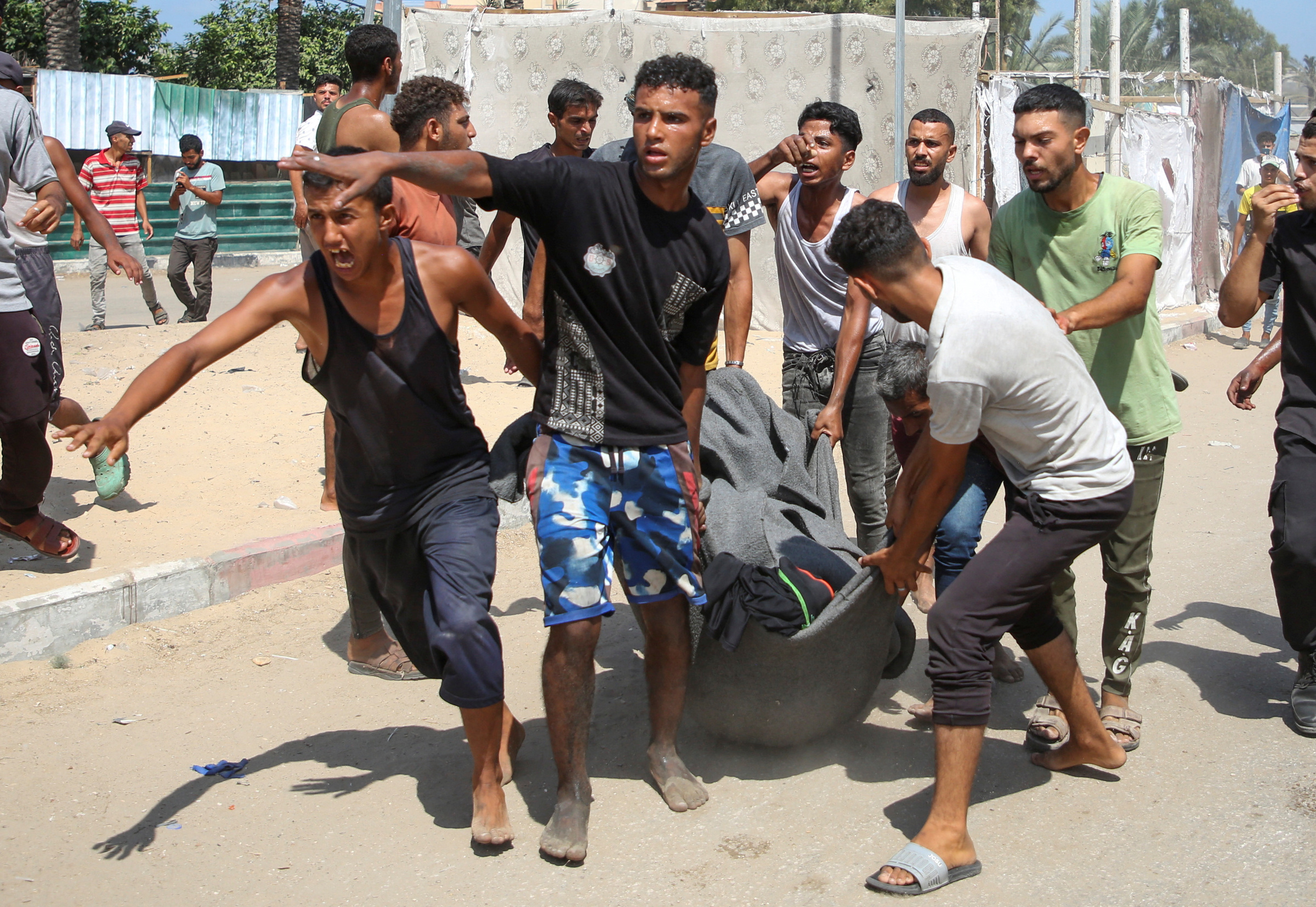 Người dân khiêng nạn nhân trong vụ tập kích lều tị nạn ở Al-Mawasi, Dải Gaza, ngày 13/7. Ảnh: Reuters