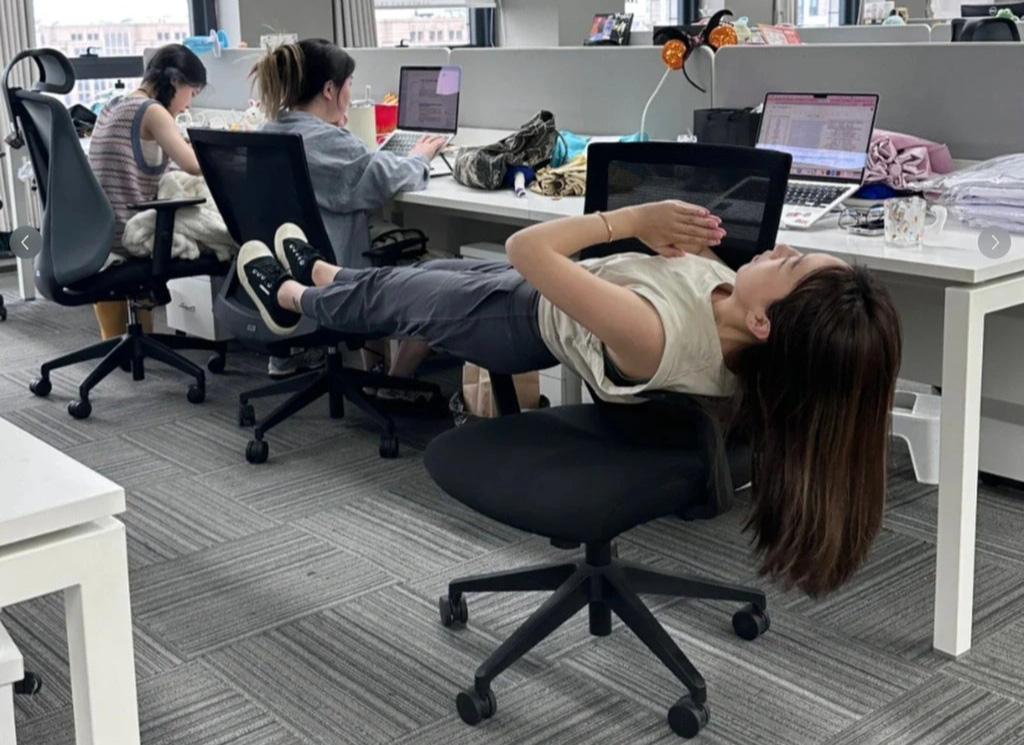 Một nhân viên văn phòng sử dụng chính ghế ngồi làm dụng cụ tập pilates - Ảnh: SCMP Dân công sở Trung Quốc biến văn phòng thành... phòng gym, đeo luôn hộp cơm thay tạ- Ảnh 4.