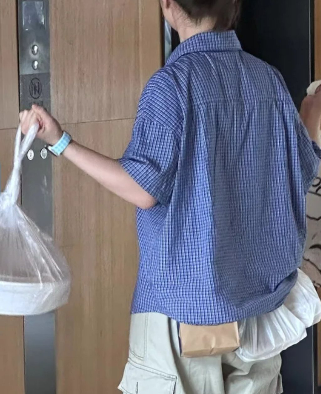 Một nhân viên văn phòng dùng túi đồ ăn trưa làm tạ để tập tay trong lúc đợi thang máy - Ảnh: SCMP Dân công sở Trung Quốc biến văn phòng thành... phòng gym, đeo luôn hộp cơm thay tạ- Ảnh 2.