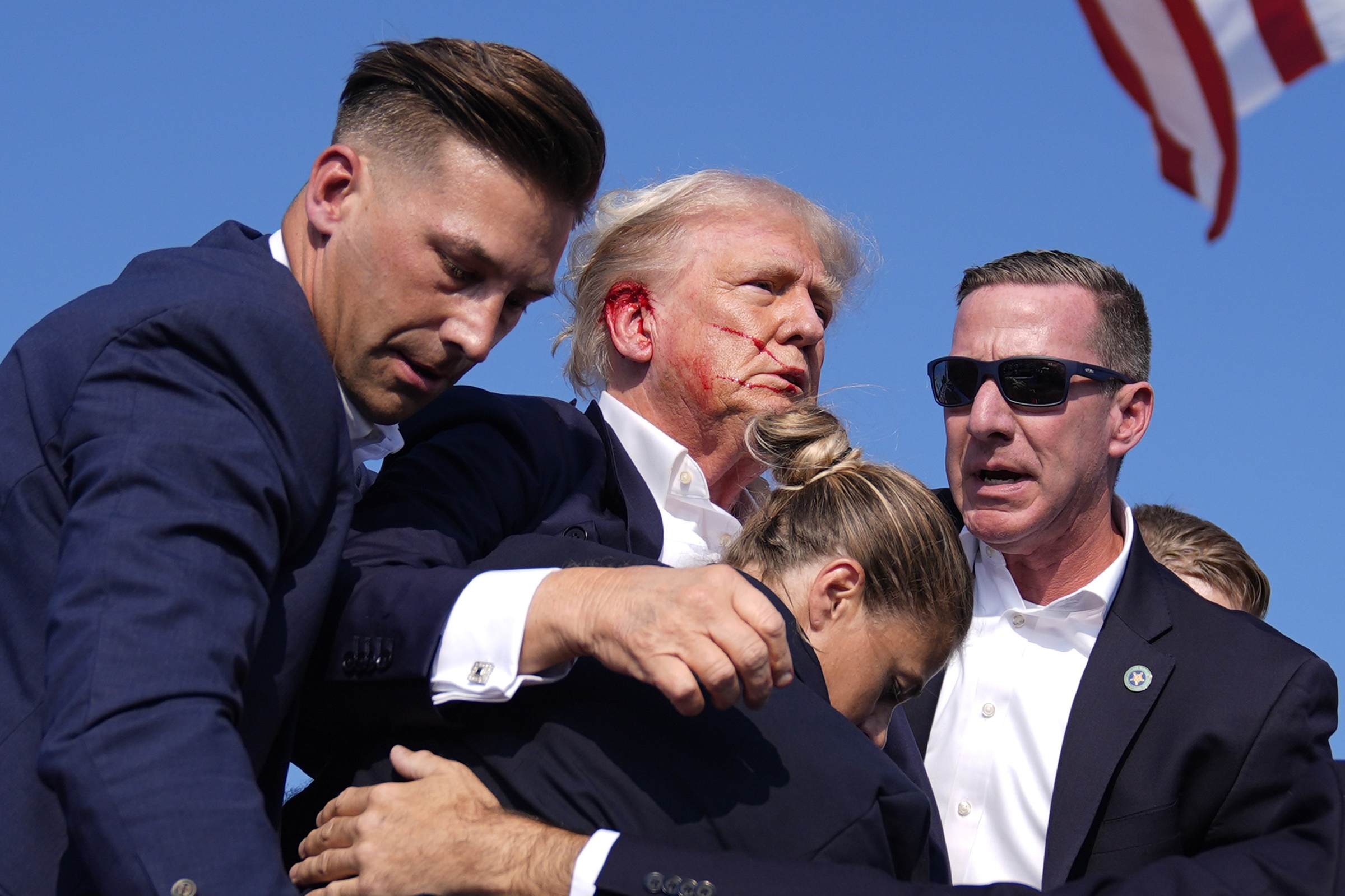 Các mật vụ đỡ ông Trump dậy và sẵn sàng di chuyển hôm 13/7. Ảnh: AP