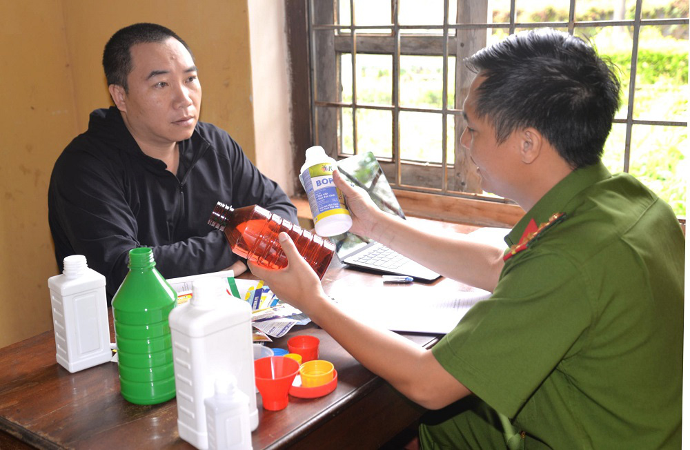 Triệt phá đường dây sản xuất thuốc trừ sâu giả quy mô lớn- Ảnh 1. Bị can Nguyễn Thái Học cùng tang vật là các chai lọ dùng chiết thuốc trừ sâu, thuốc diệt cỏ giả - Ảnh: Công an tỉnh Gia Lai