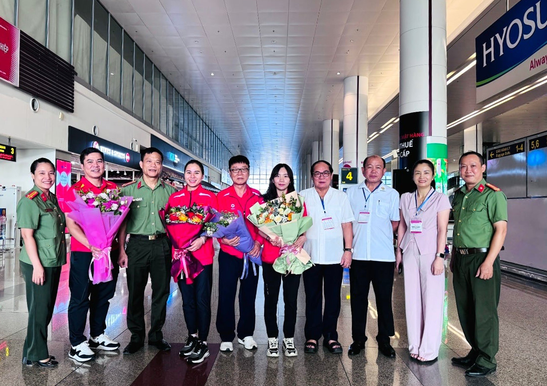 Thu Vinh (thứ tư từ bên trái) và các thành viên tuyển bắn súng Việt Nam nhận hoa chúc mừng khi trở về Hà Nội. Ảnh: Việt Anh.