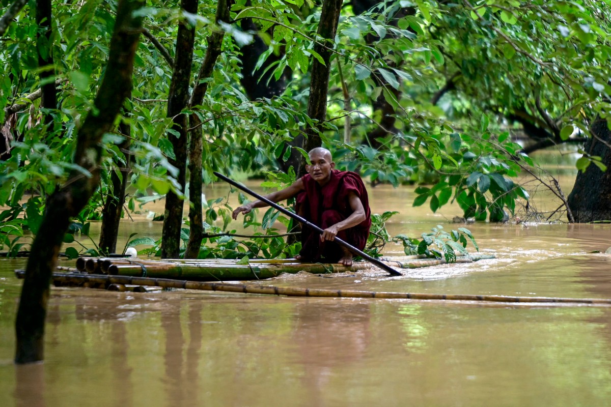 Nhà sư chèo bè kết bằng thân tre vượt lũ ở Taungoo, Myanmar, ngày 14/9. Ảnh: AFP