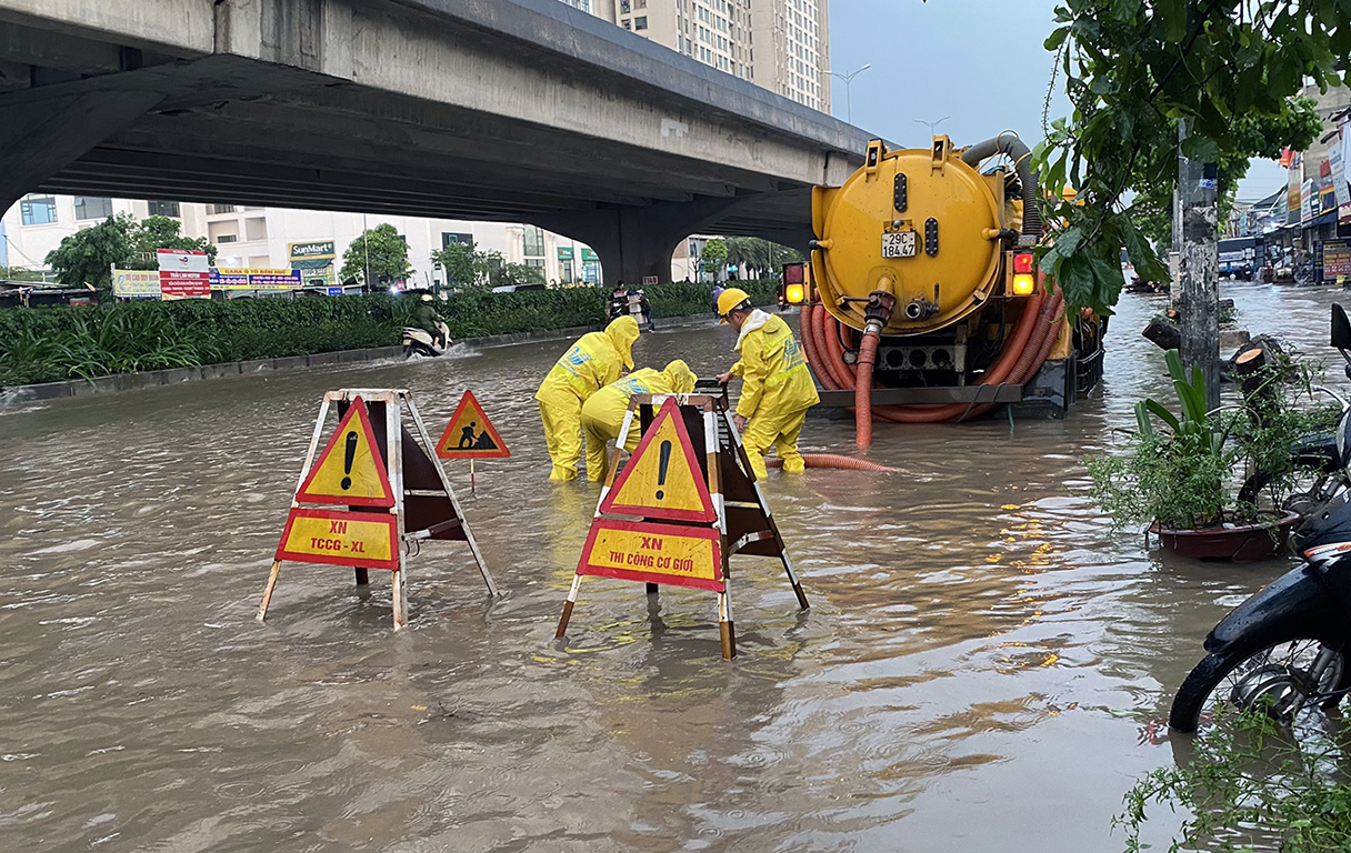 Công ty thoát nước đặt biển cảnh báo, khơi thông miệng cống trên đường Nguyễn Xiển. Ảnh: Hoàng Phong