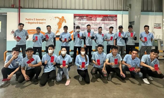 Công nhân Công ty Motomotion Việt Nam (Bình Dương) chụp ảnh kỷ niệm khi nhận lì xì 500.000 đồng trong ngày làm việc đầu năm 3/2 (mùng 6 Tết). Ảnh: An Phương