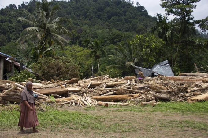 Người dân bước qua đống gỗ bị lũ quét cuốn vào, tỉnh Tây Sumatera, Indonesia, 13/3/2024. Ảnh: AP